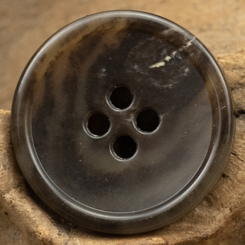 Black round 4-hole urea-look button with slim edge and imitation fruit texture