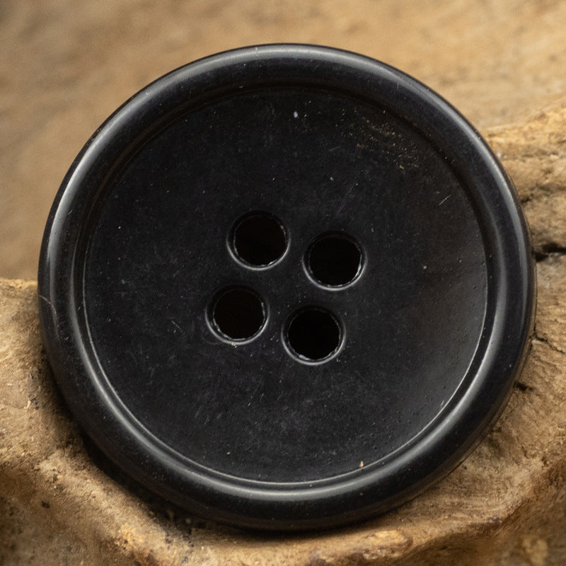 Black round 4-hole urea-look button with slim edge, fruit-texture imitation