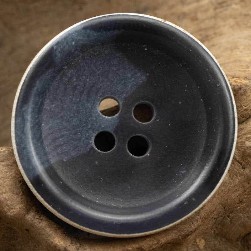 Dark blue urea button close-up, four large holes on front face