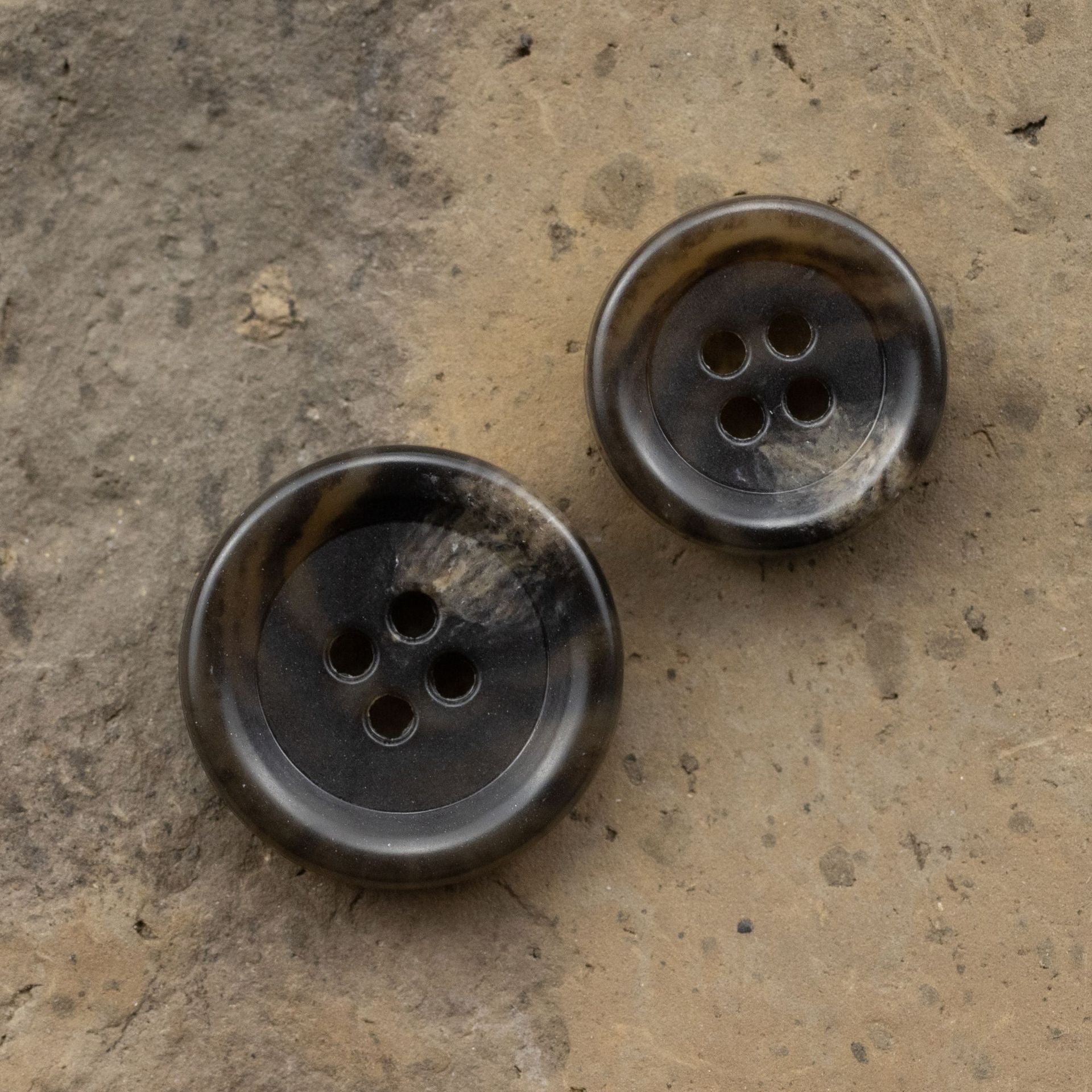 Two dark brown urea buttons, 4-hole faces with mottled leopard print