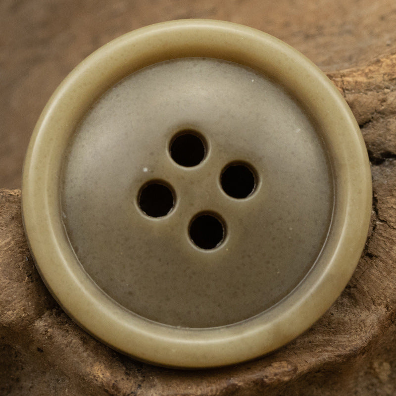 Round 4-hole urea coat button in light tan/brown with smooth edge
