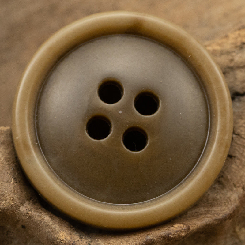 Round 4-hole urea coat button in muted tan/brown with smooth rim