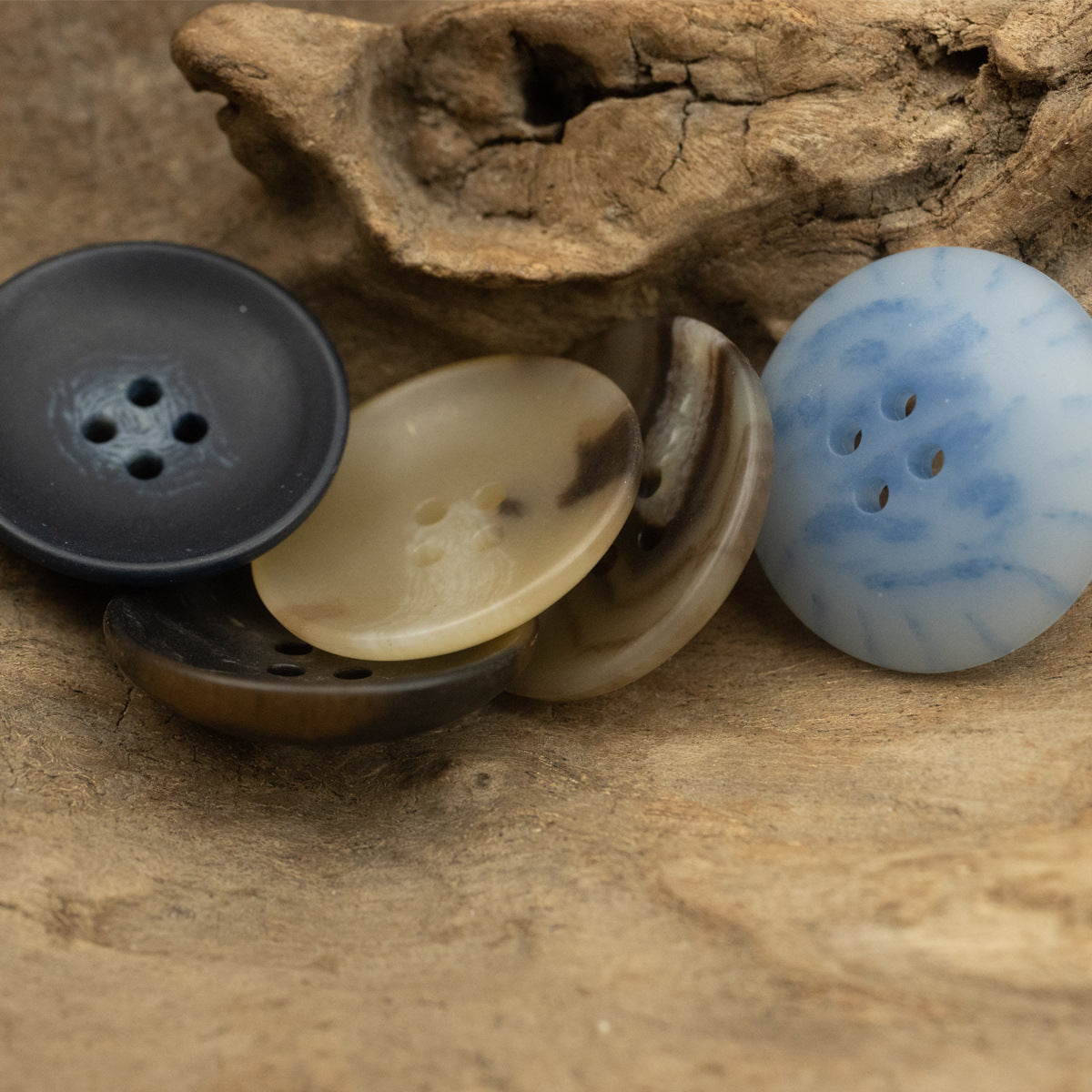 4-Loch Schalenknöpfe in Schwarz, Creme und Hellblau (Urea), mehrere Lagen sichtbar