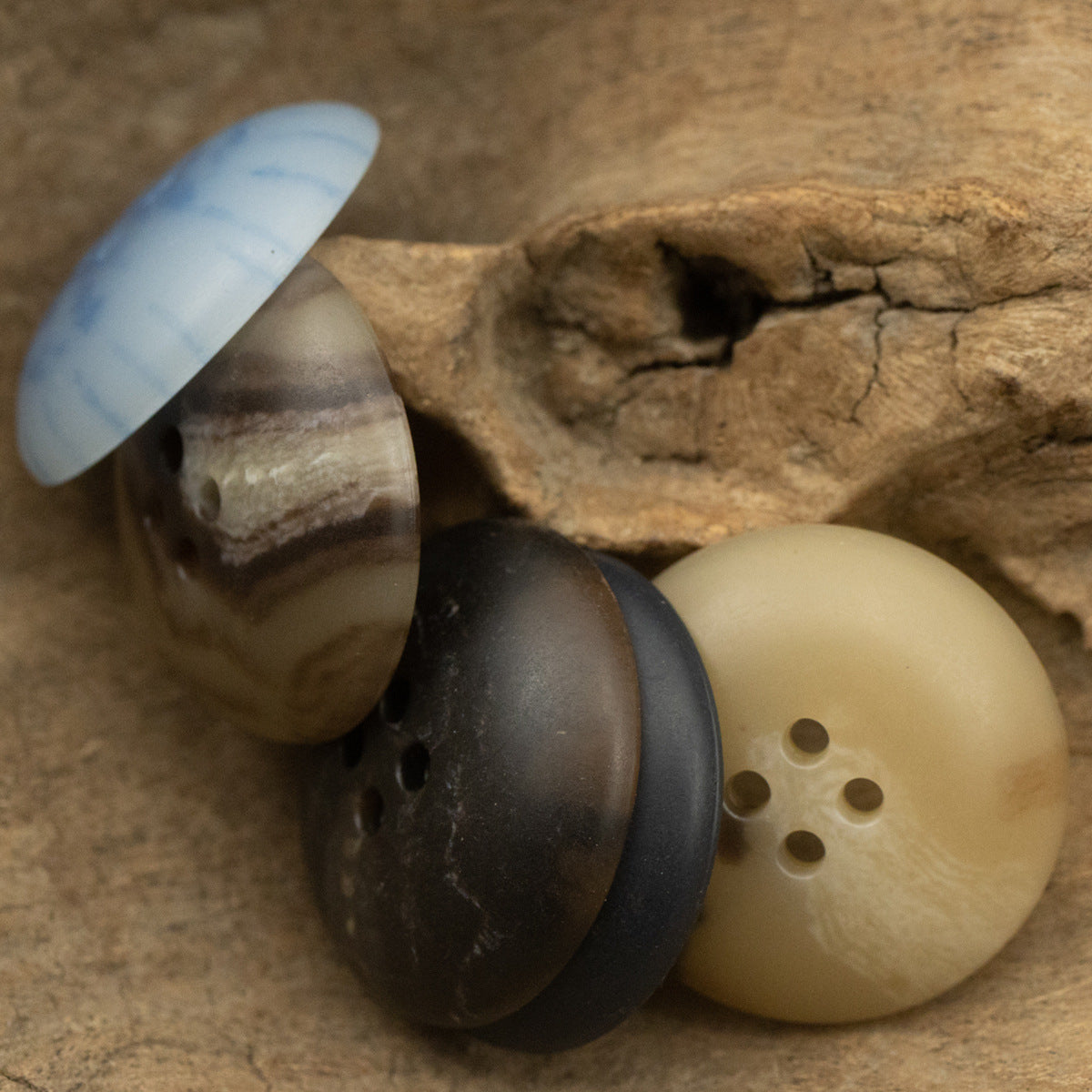 Round four-hole urea buttons: light cream and dark charcoal (front view)