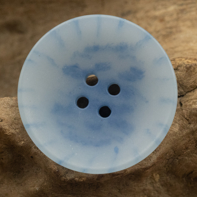Light blue round four-hole urea button with subtle marbled speckles