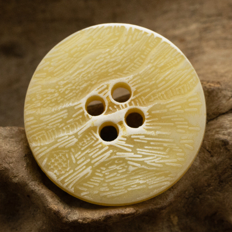 Yellow imitation bark button with four holes and distressed texture