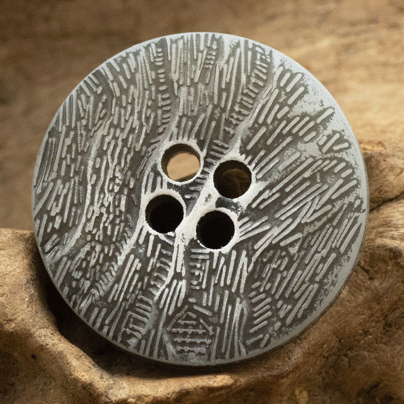 Dark grey imitation bark button with four holes and distressed texture