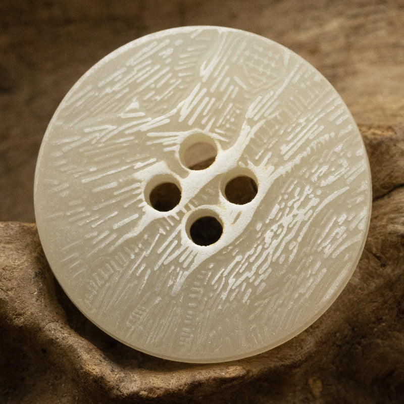 Off-white imitation bark button with four holes and distressed texture