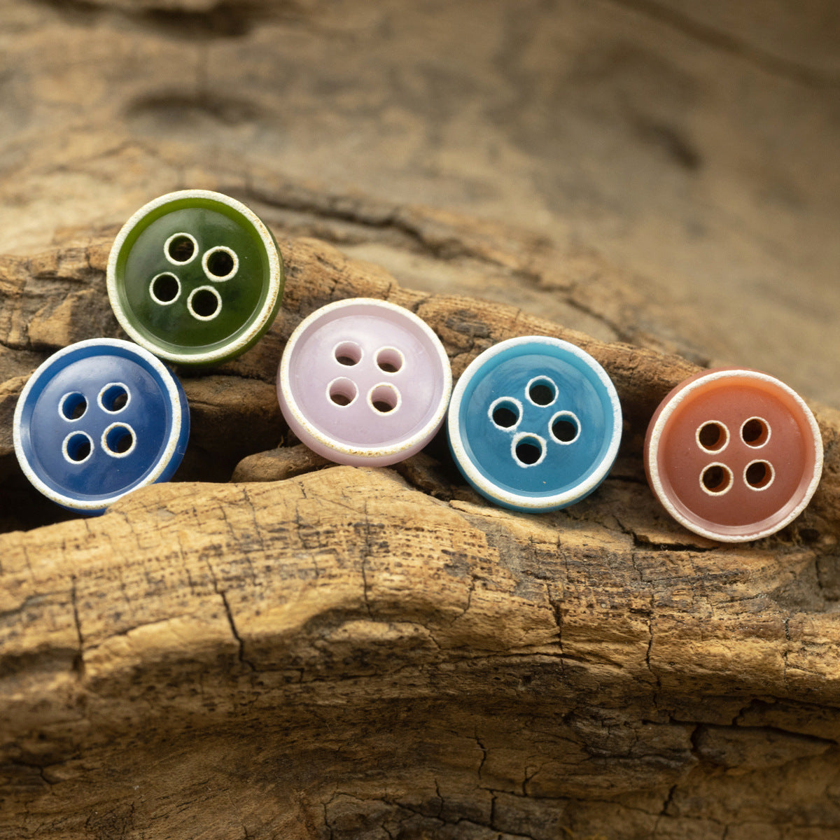 Close-up of 4-hole round buttons: green, pale pink, light blue, orange