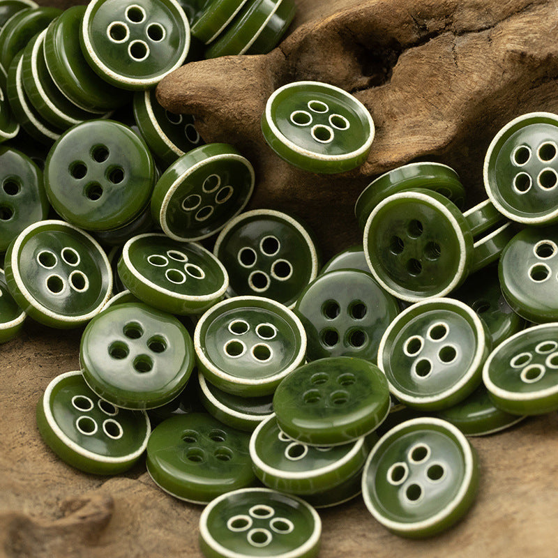 Mixed green 4-hole round buttons with white rim detail, scattered on wood