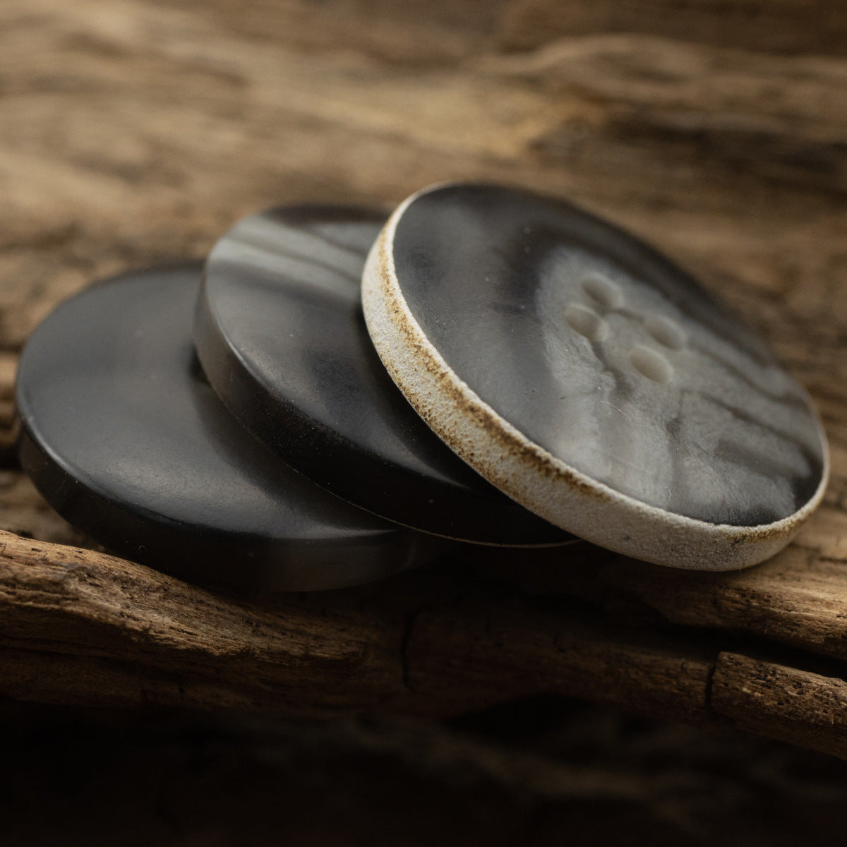 Pair of dark gray-black vintage buttons with textured finish and burnt rim, 4 holes
