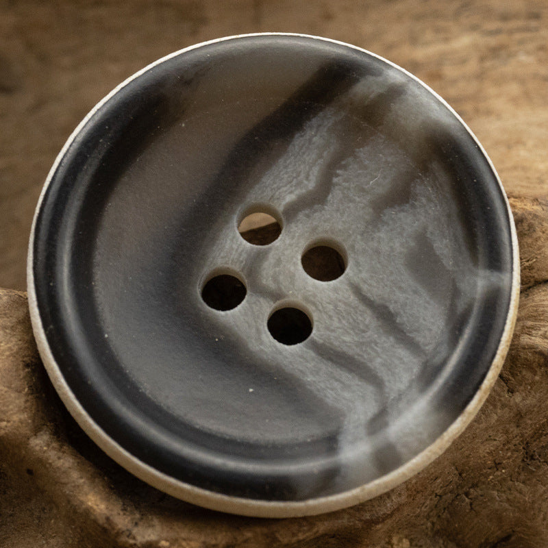 Smaller view of dark gray-black 4-hole urea button with textured surface