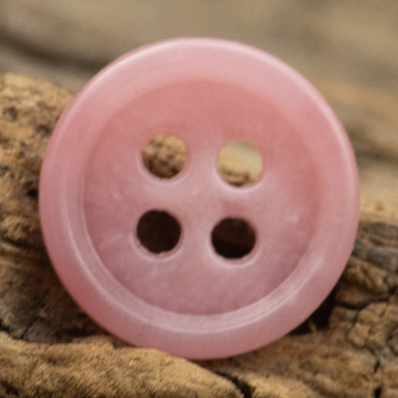 Pink round urea shirt button (4-hole) close-up
