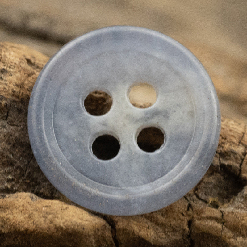 Light blue round urea shirt button (4-hole) close-up