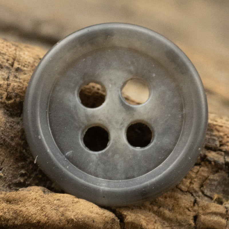 Light gray round urea shirt button (4-hole) close-up