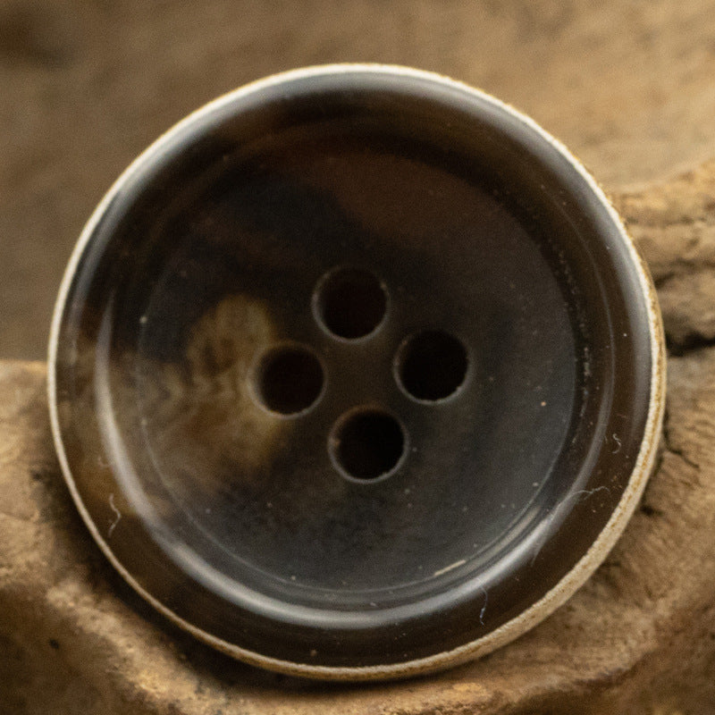 Close-up dark-brown urea coat button, 4-hole design with burnt-edge rim