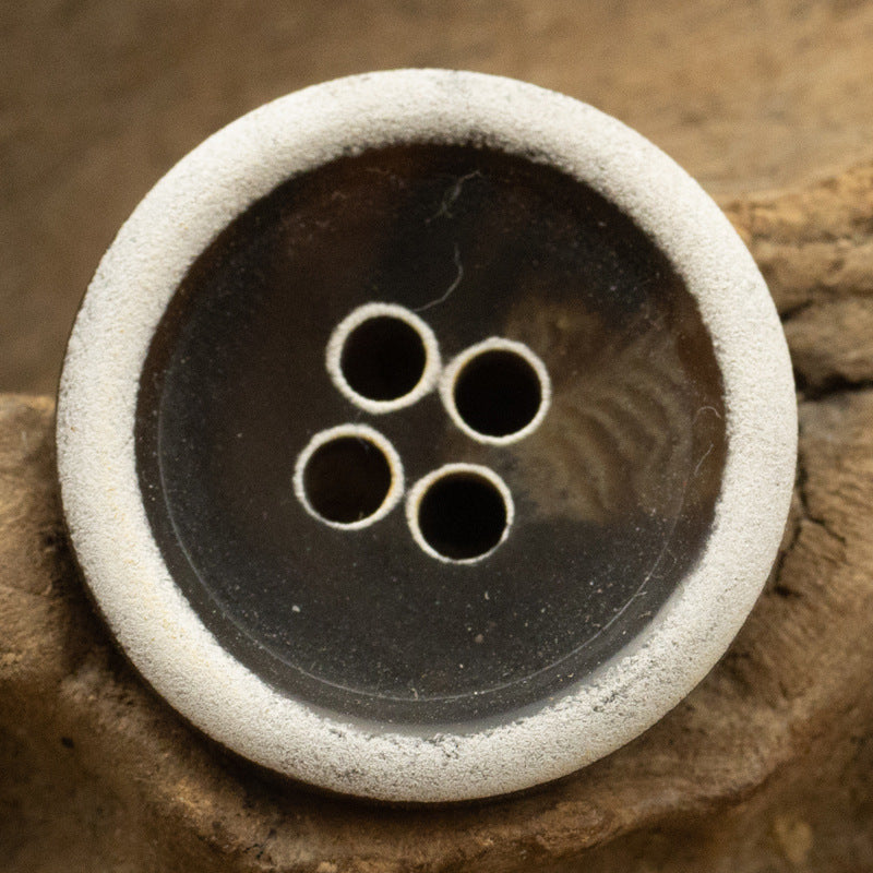 Dark-brown urea coat button with light burnt-edge rim, 4 holes