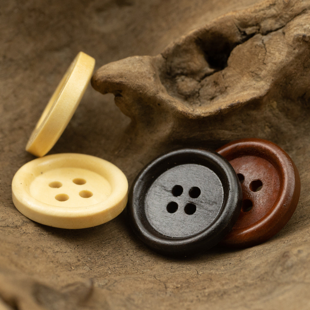 Four-hole wooden buttons: light yellow, charcoal gray, and brown (3 shown)