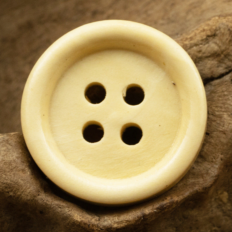 Light yellow vintage round wooden button with four holes and a smooth face