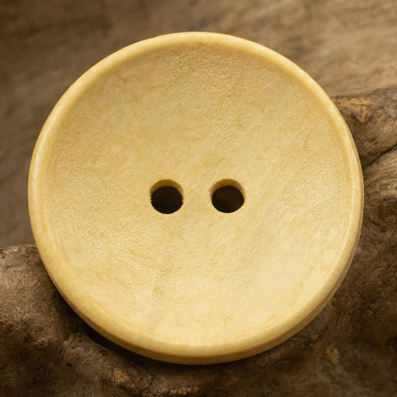 Two-hole dotted wood button, natural light wood tone, bowl-shaped front view