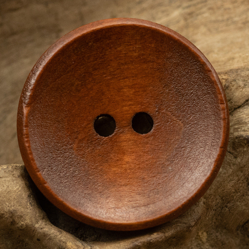 Two-hole dotted wood button, coffee brown wood tone, bowl-shaped front view