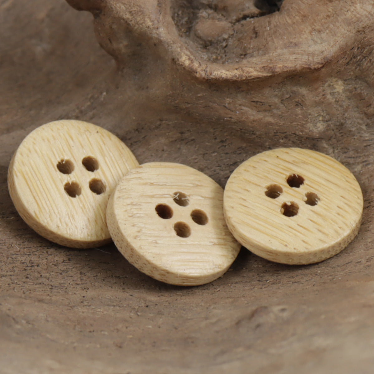 Set of natural bamboo round buttons in light tan, each with four holes.