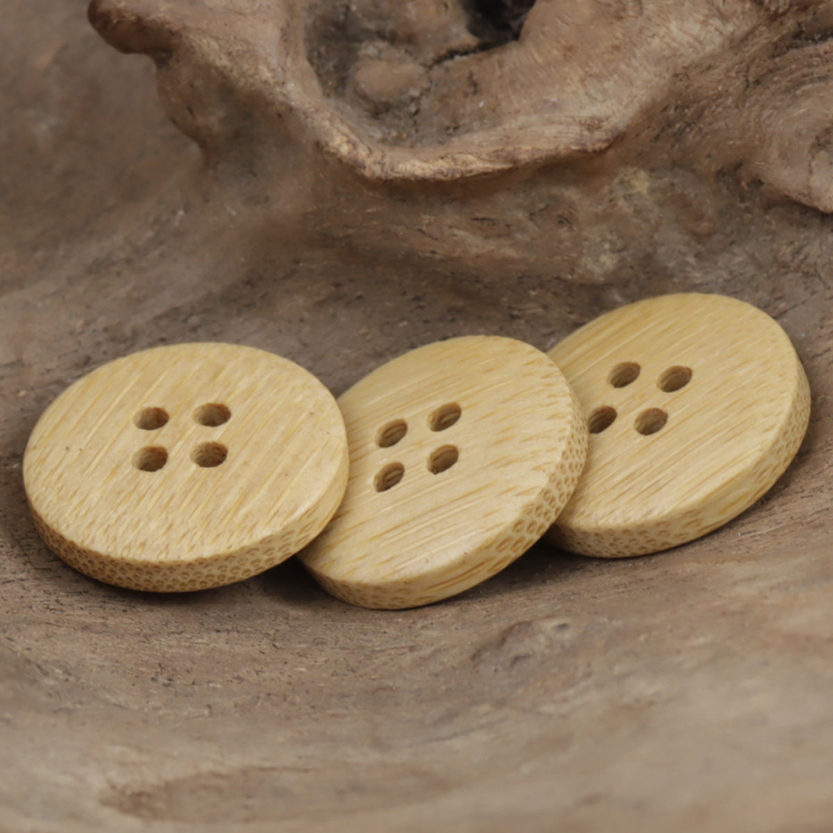 Three round bamboo buttons with four-hole design, light tan wood grain