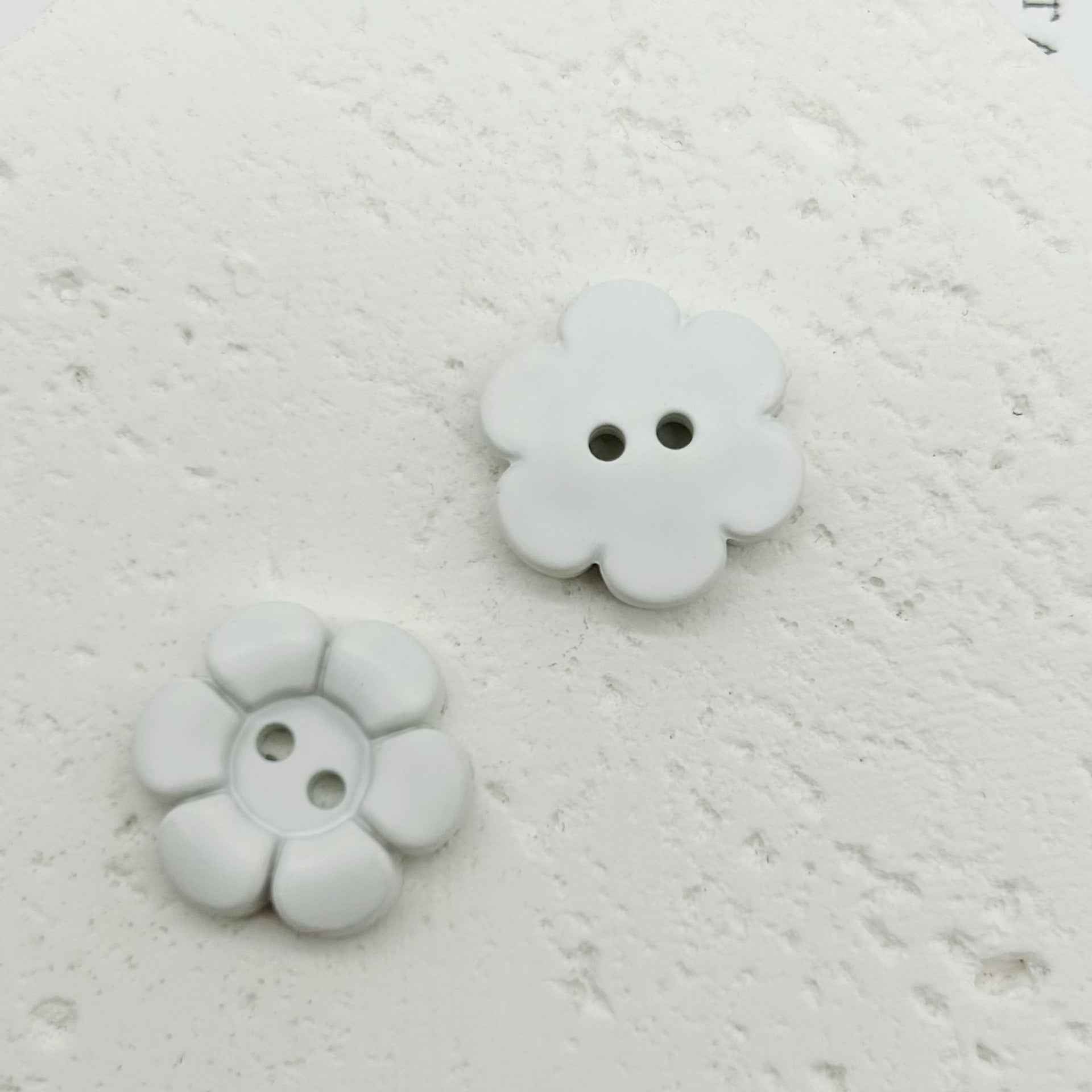 Weiße blumenförmige Kunststoffknöpfe mit zwei Löchern, großes und kleines Paar