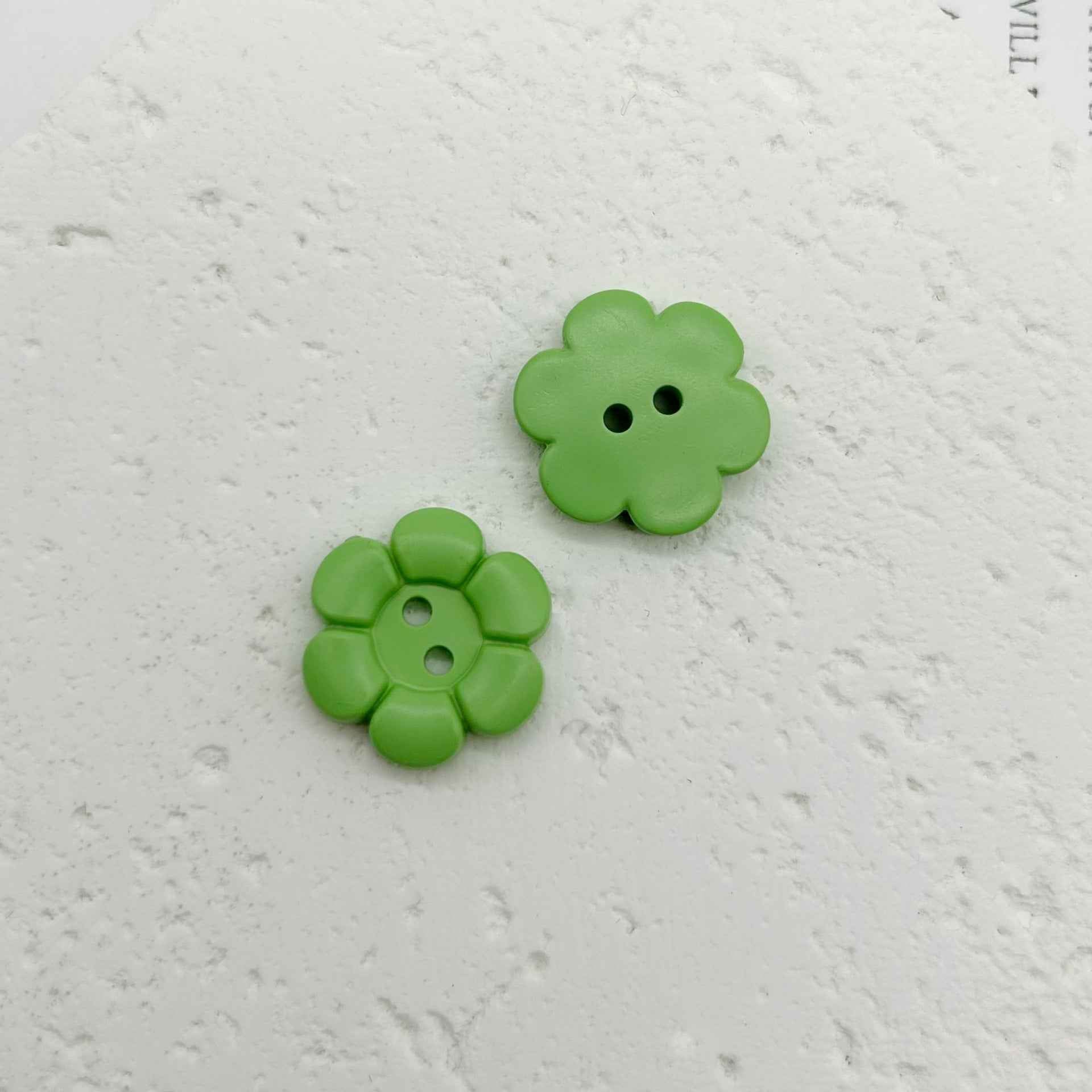 Grüne blumenförmige Kunststoffknöpfe mit zwei Löchern, 2 Stück