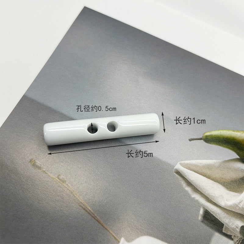 White long resin toggle button, two holes; ~5cm x ~1cm