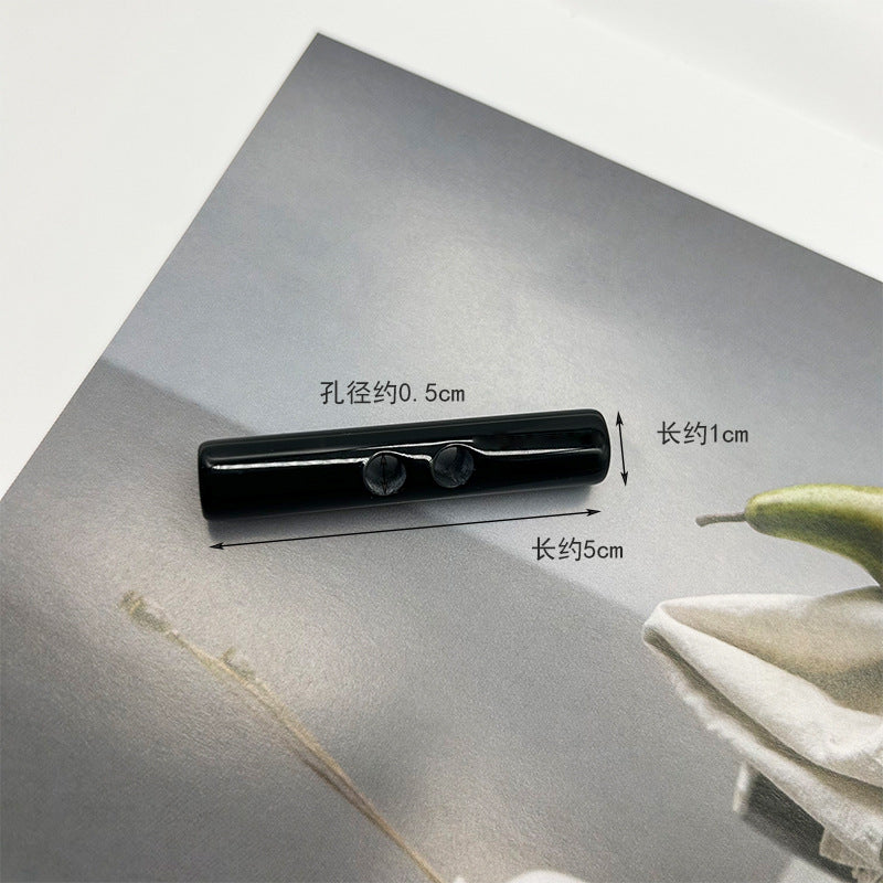 Black long resin toggle button, two holes; ~5cm x ~1cm