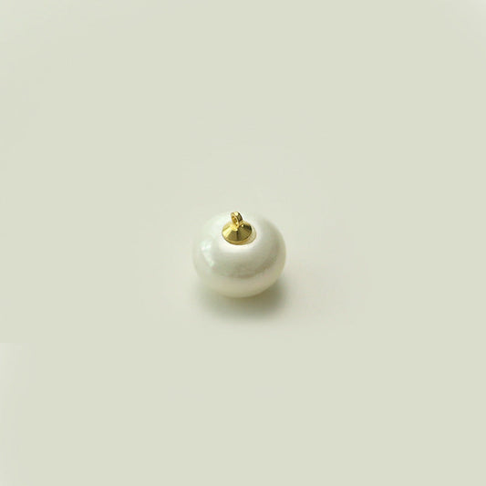 Round oblate white pearl button showing gold-tone metal shank from underside