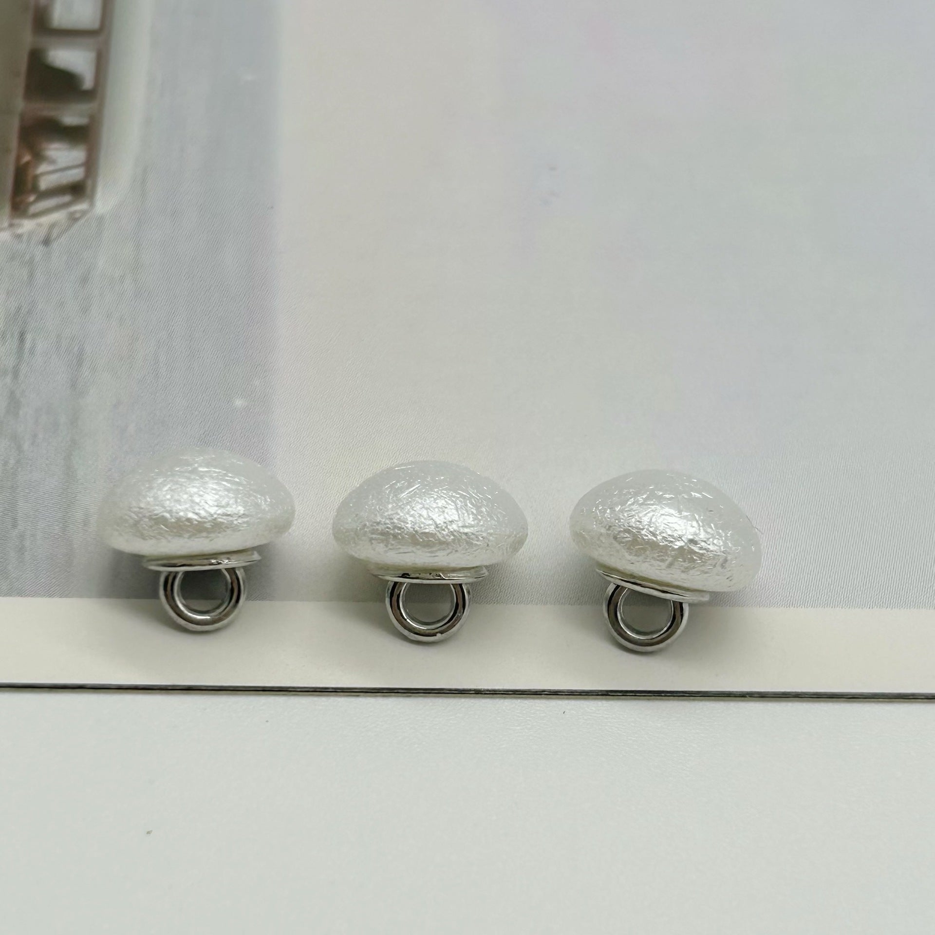 Round wrinkled pearl buttons with metal shanks, glossy silvery white fronts