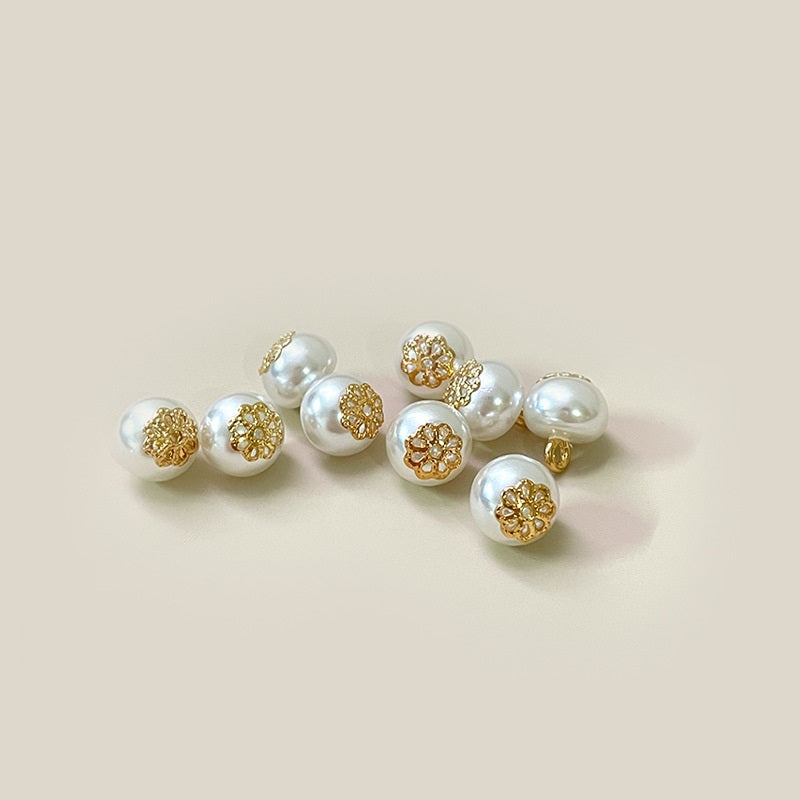 Set of white plastic pearl buttons with gold-tone flower design and shanks