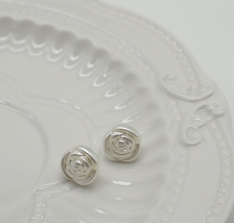 Two white pearl rose buttons with metal shanks on embossed white plastic