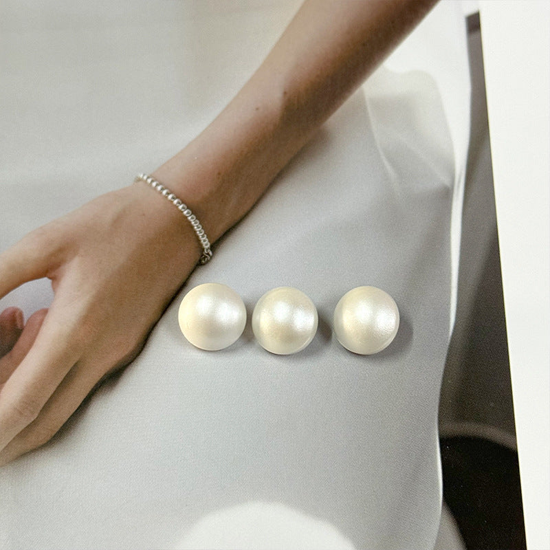 Three 11.5mm white pearl buttons on shirt cuff or placket