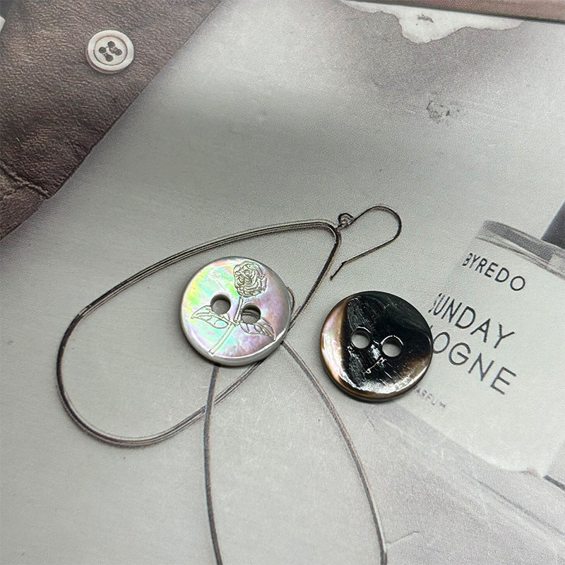 Iridescent round two-hole rose-pattern shell button on light fabric