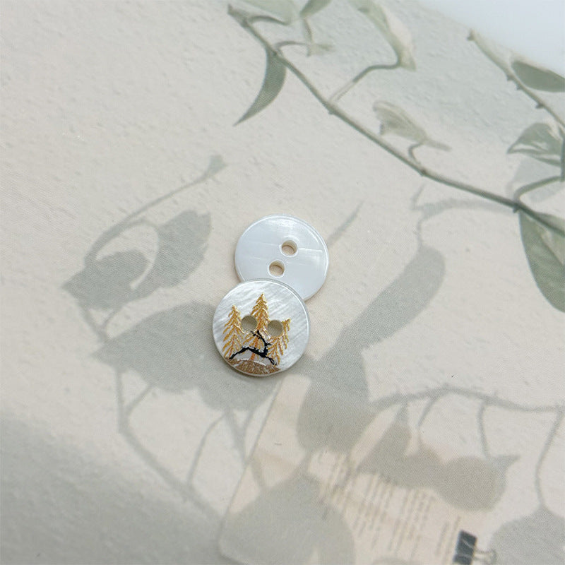 Two-hole shell button with deer and pine trees design, light base
