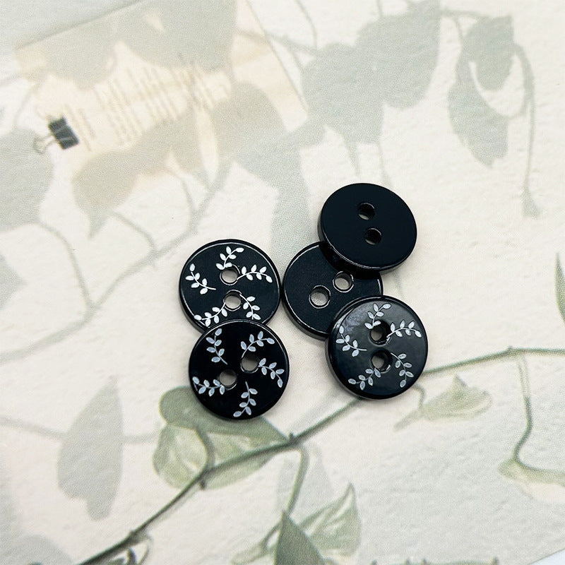 Black round 2-hole flat buttons with white willow leaf pattern, shown from different angles