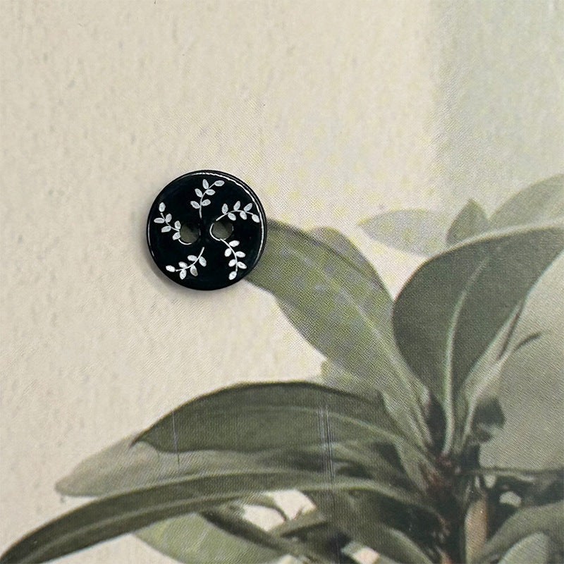 Black round 2-hole flat button with white willow leaf vine design