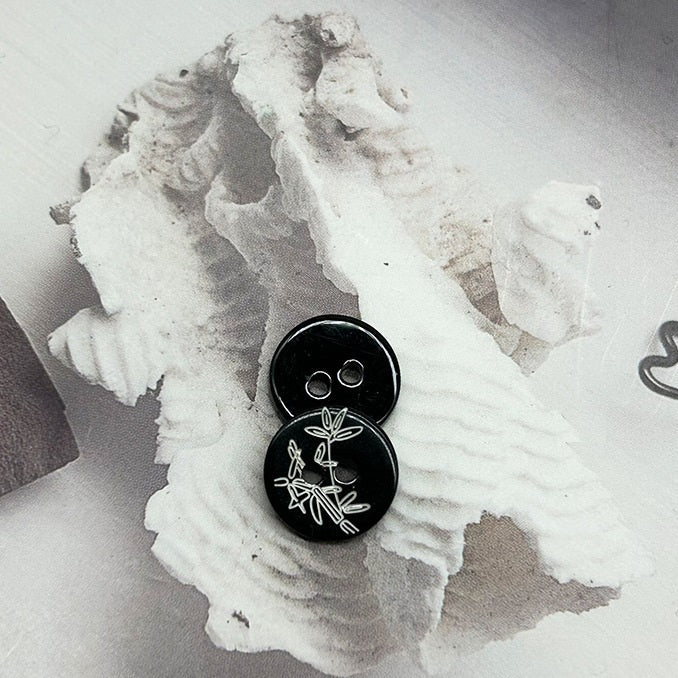 Black 2-hole round shirt buttons with bamboo motif, close-up pair