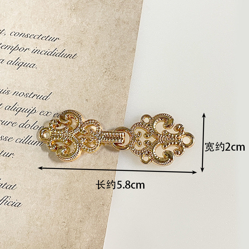 Gold-tone metal frog button with detailed filigree scrolls and decorative fastening loops