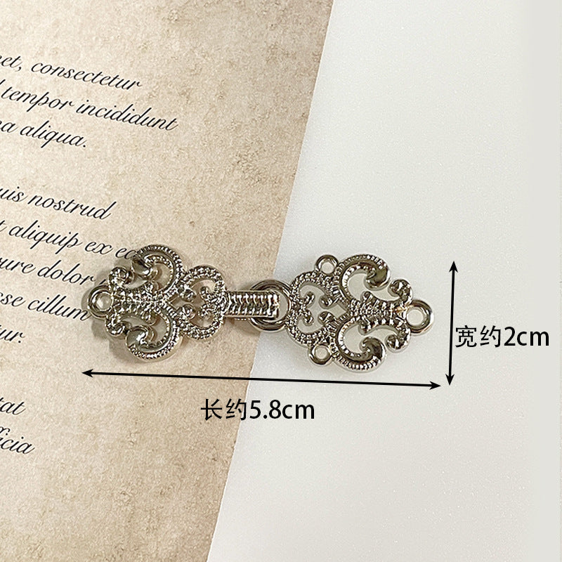 Silver-tone metal frog button with intricate filigree scrolls and decorative fastening loops
