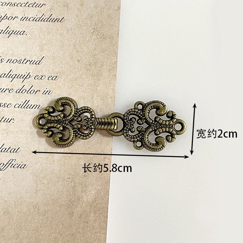 Antique bronze metal frog button, ornate filigree toggle with leaf-and-scroll detailing