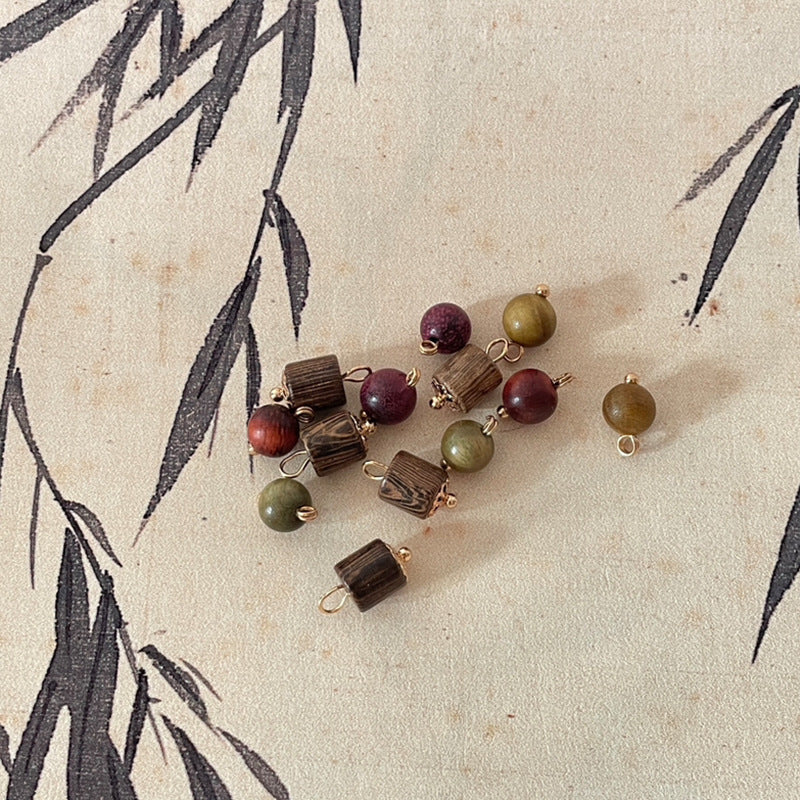 Wooden bead charms with gold loops, including burgundy and olive round beads.