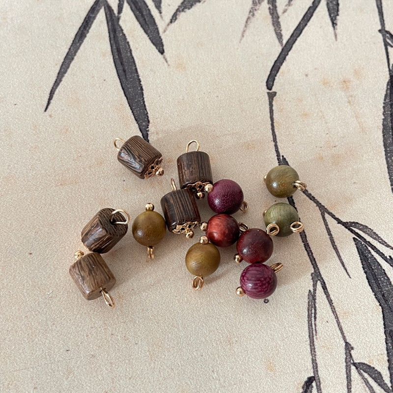 Assorted wooden bead charms with gold loops and small floral caps (brown, red, green).