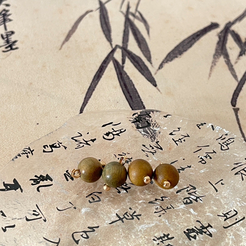 Olive green wooden bead charms with gold loops and round beads.