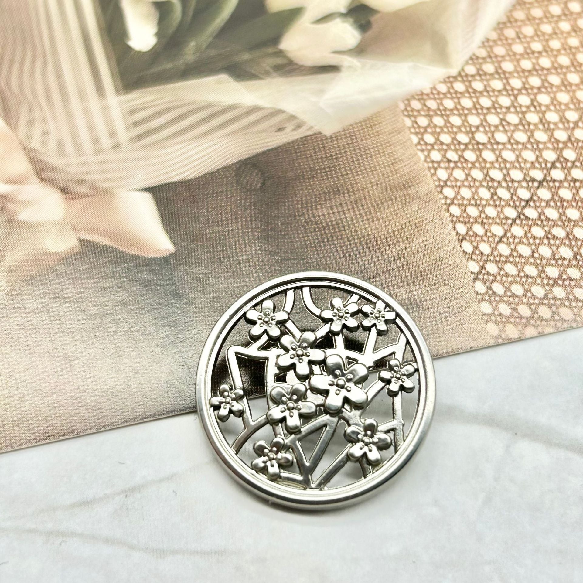 Matte silver metal button with plum blossom floral cutout pattern, hollow shank