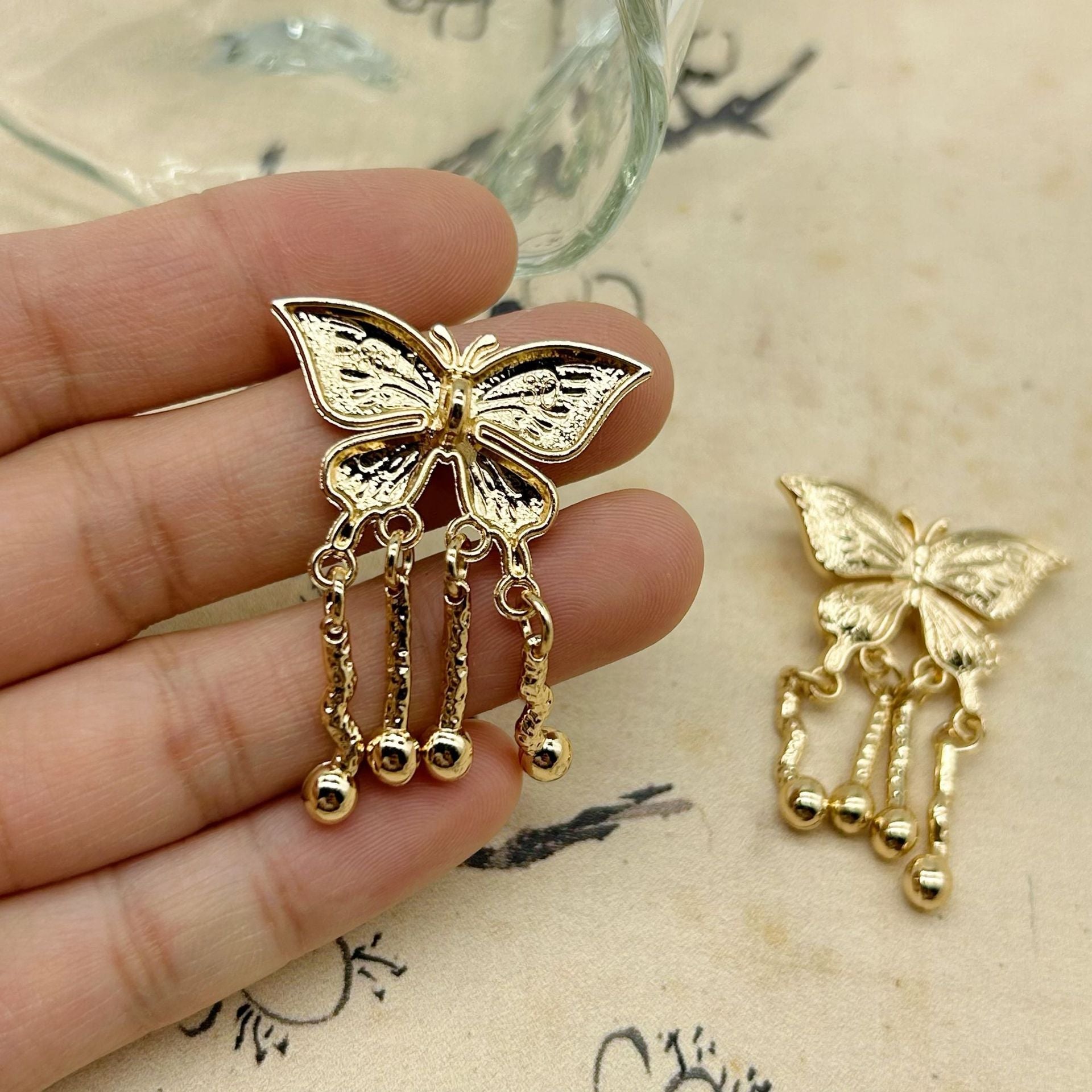 Pair of golden butterfly metal buttons with chain tassel dangles and bead tips
