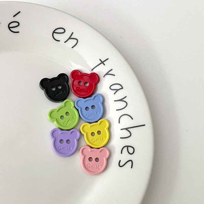 Cartoon teddy bear face buttons: red, black, green, yellow, purple, pink, each with two holes